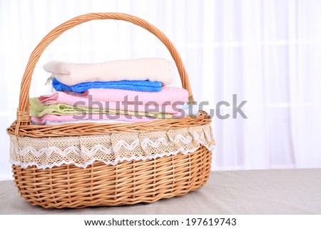 Colorful towels in basket on light background