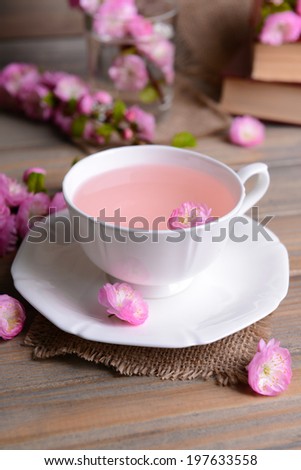 Beautiful fruit blossom with cup of tea on table on grey background