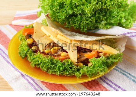 Veggie wrap filled with cheese and fresh vegetables on table, close up