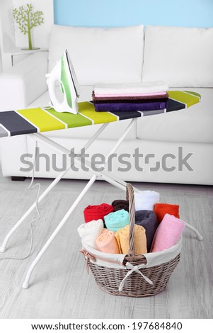 Basket with laundry and ironing board on home interior background
