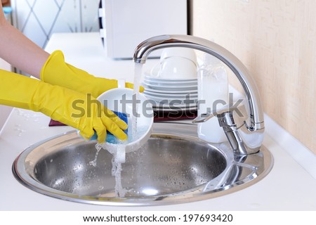 Close up hands of woman washing dishes in kitchen