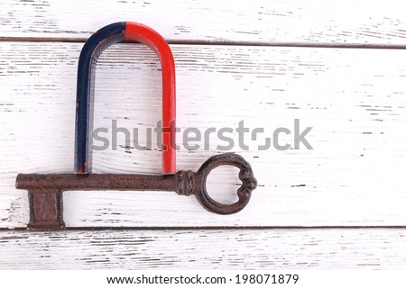 Magnet with old key on wooden background