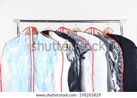 Office female clothes in cases for storing on hangers, on gray background