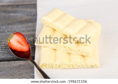 White chocolate bar on napkin on color wooden background