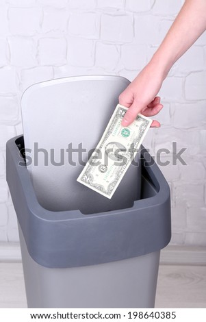 Throwing away your money on grey wall background