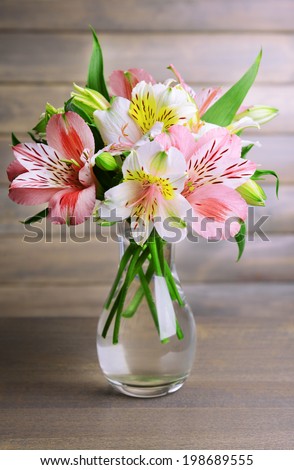 Alstroemeria flowers in vase on table on grey background