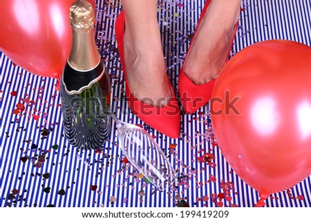 Legs with confetti, champagne and balloons on the floor