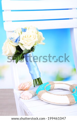 Beautiful wedding bouquet with roses on wooden chair, on nature background