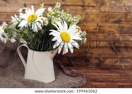 Beautiful bouquet of daisies in decorative vase on wooden background