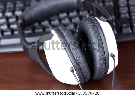 Headphone and keyboard close-up on wooden desk background