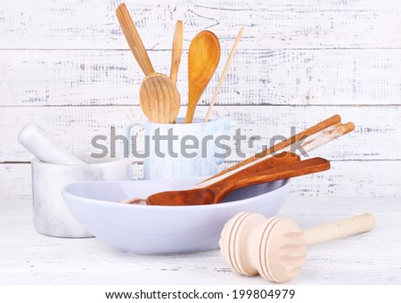 Composition of wooden cutlery, mortar, bowl on wooden background