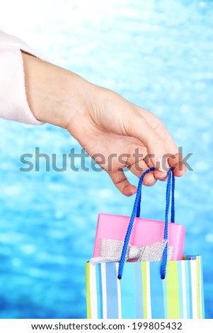 Hand holds package with New Year gift on blue background