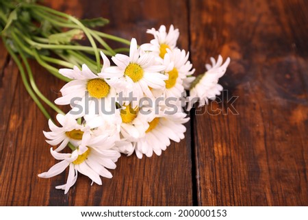 Beautiful bouquet of daisies on wooden background