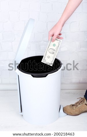 Throwing away your money on grey wall background