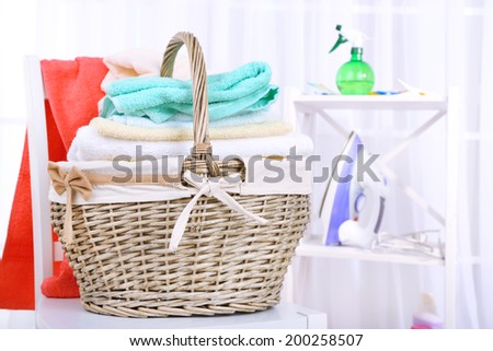 Colorful towels in basket on chair, on home interior background