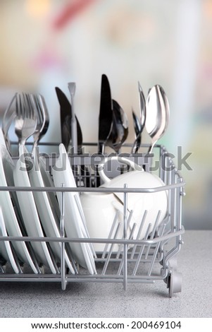 Clean dishes drying on metal dish rack on light background
