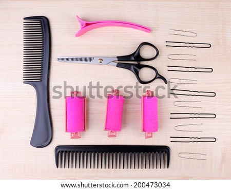 Professional hairdresser tools - comb, scissors and pins on light wooden background