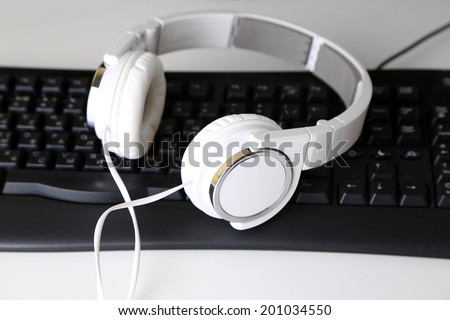 Headphone and keyboard close-up on white desk background