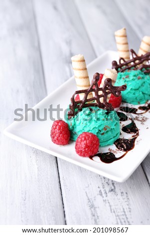 Tasty ice cream with chocolate decorations and sauce plate, on color wooden  background