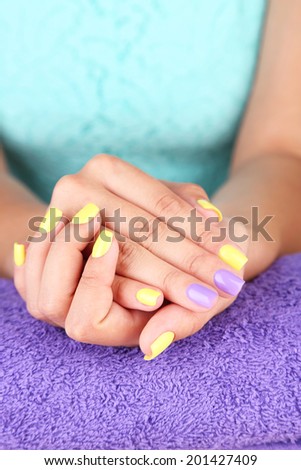 Female hand with stylish colorful nails, on color towel, close-up