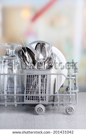 Clean dishes drying on metal dish rack on light background