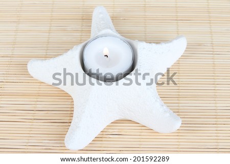 Candle in starfish on bamboo napkin close-up