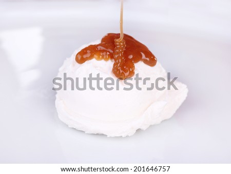 Vanilla ice cream with caramel sauce on white plate, close-up