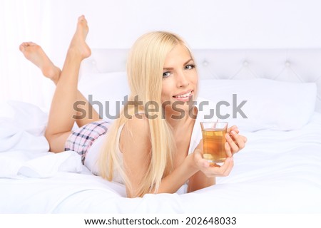 Young beautiful woman with cup of tea in bed