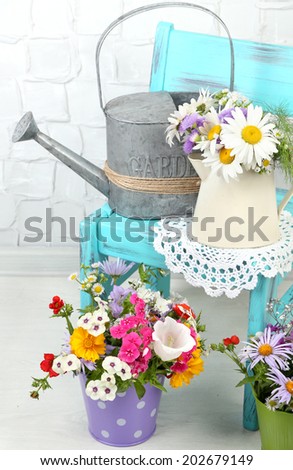 Bouquet of colorful flowers in decorative buckets, on chair, on home interior background