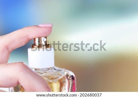 Bottle of perfume in hand on bright background