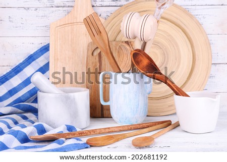 Composition of wooden cutlery, mortar, bowl and cutting board on wooden background