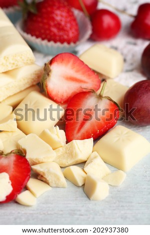 White chocolate bar with fresh berries, on color wooden background