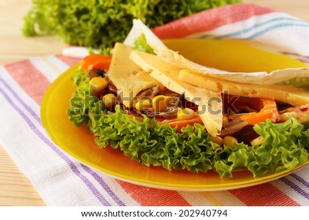 Veggie wrap filled with cheese and fresh vegetables on table, close up