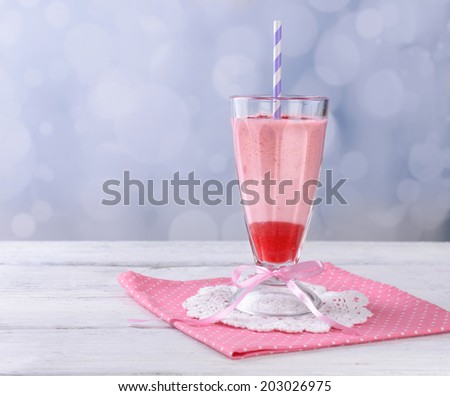 Glass of raspberry smoothie drink on wooden table, on light background