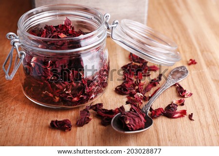 Dried hibiscus tea in glass jar, brown sugar  in box on wooden background