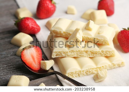 White broken chocolate bar on napkin on color wooden background