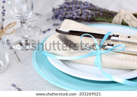Dining table setting with lavender flowers on light tablecloth background