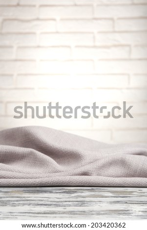 Wooden table with cloth on wall background