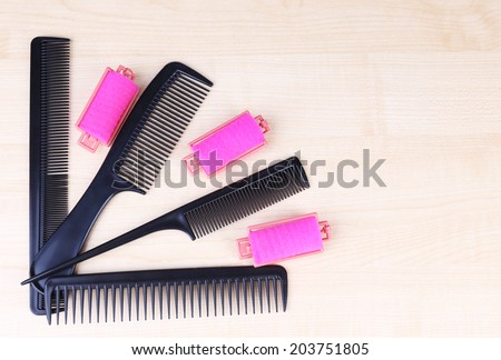 Professional hairdresser tools - comb, scissors and curlers on light wooden background