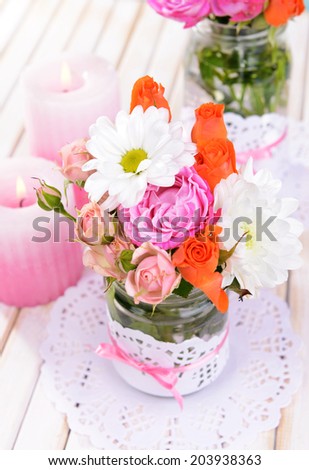 Beautiful bouquet of bright flowers in jars on table close-up