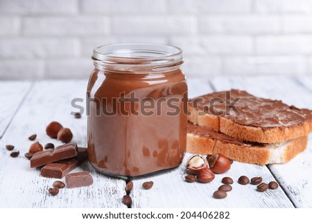 Sweet chocolate cream in jar on table on light background