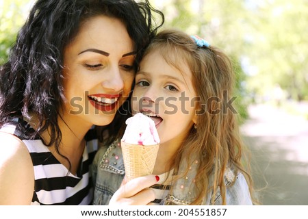 Happy mom and daughter in the green park with ice cream