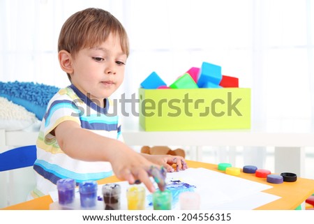 Cute little boy painting in room