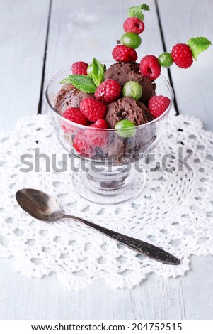 Chocolate ice cream with mint leaf and  ripe berries in glass bowl, on color wooden background