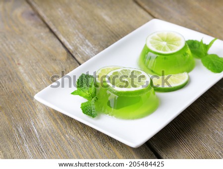 Green jelly with mint leaves and lemon lime slices on wooden background