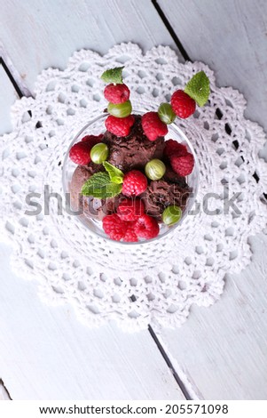 Chocolate ice cream with mint leaf and  ripe berries in glass bowl, on color wooden background