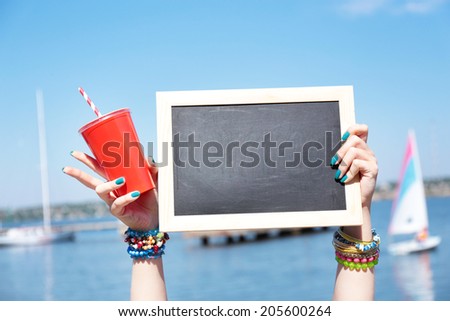 Blank chalkboard in female hand on beach background