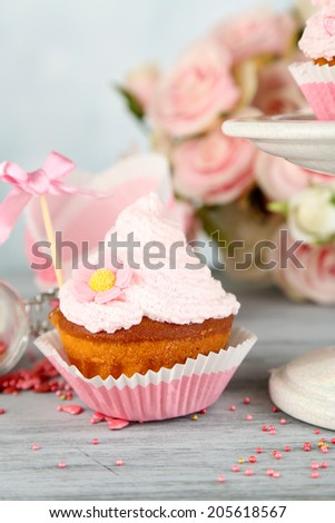 Tasty cup cake with cream on grey wooden table