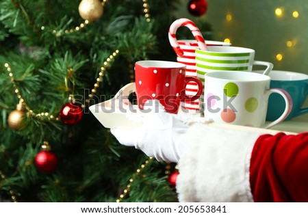 Santa holding  tray with mugs in his hand, on bright background