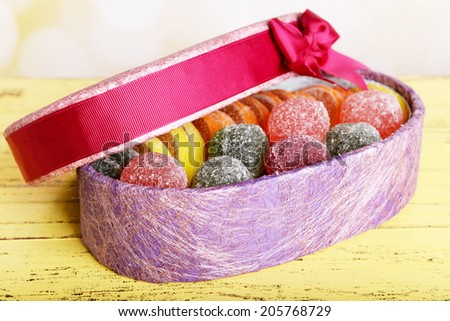Present box with sweets on table on bright background
